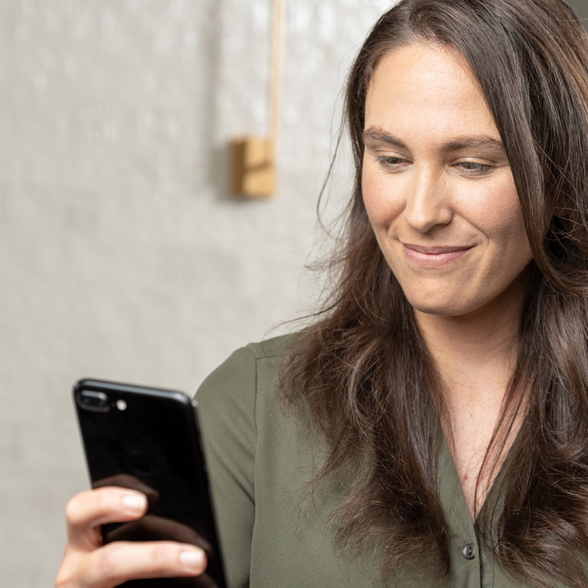 A woman uses her phone to browse targeted product offers from her financial institution.