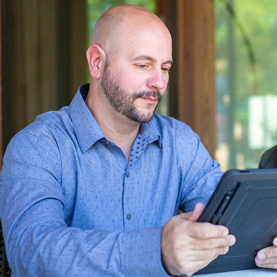 A man uses a tablet to review product offers from his financial institution made possible through the Digital Storefront.