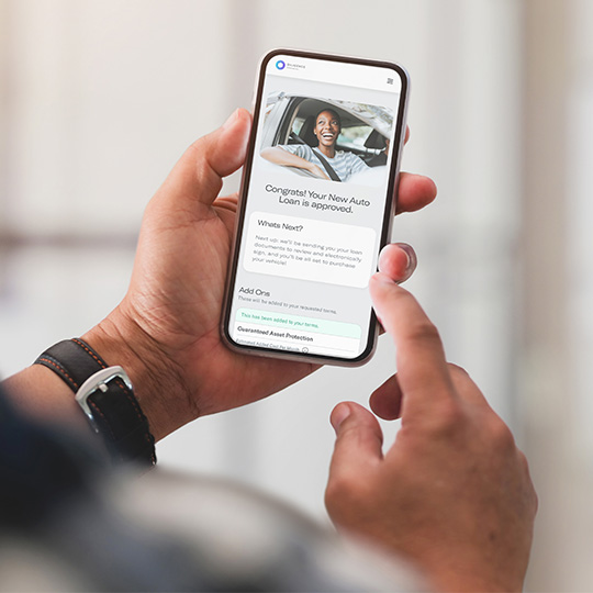 A consumer uses their phone to complete an auto loan application made available through use of the Digital Storefront.
