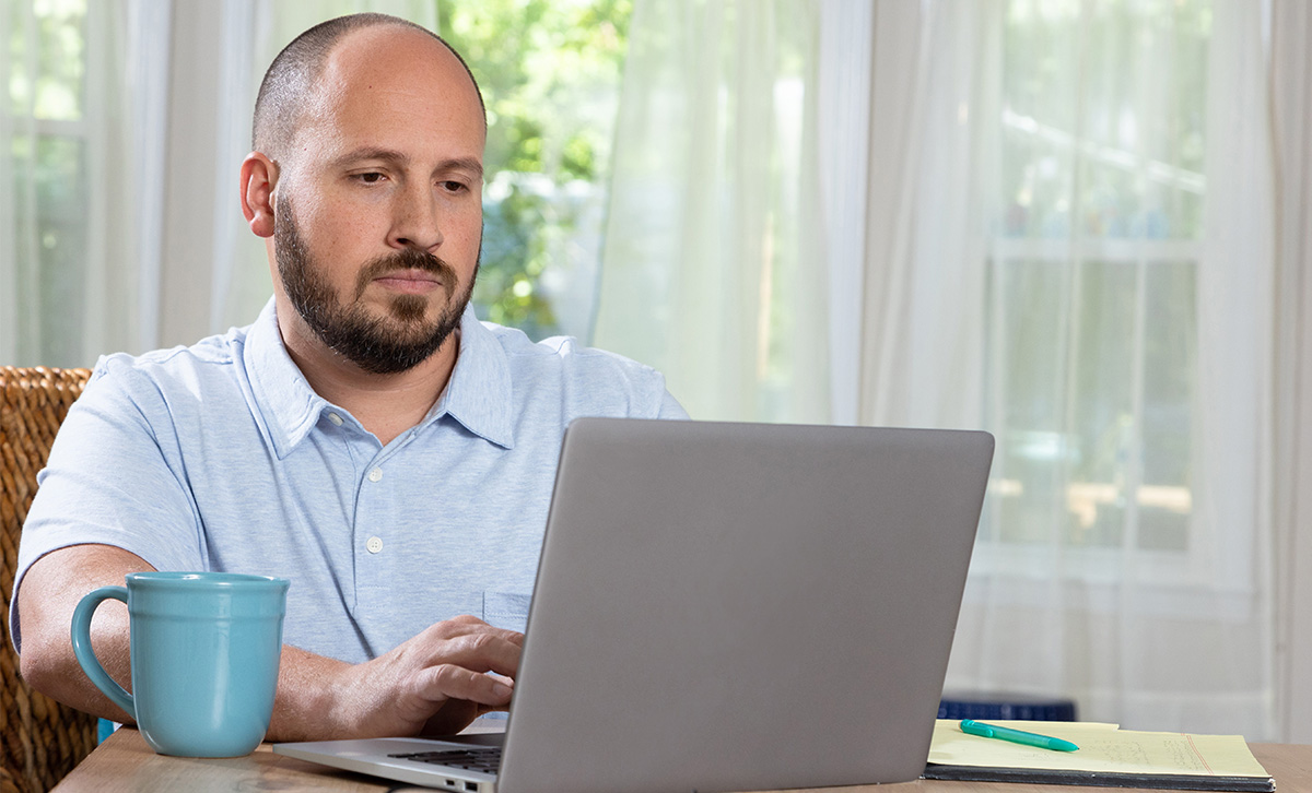 A man on a laptop reviews product offerings from his financial institution made possible through the Digital Storefront.