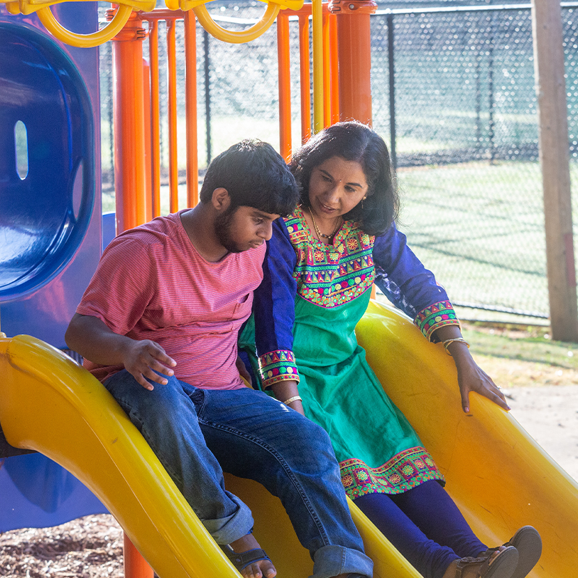 Adolescent male and woman on playground slide thinking about Charitable Donation Accounts
