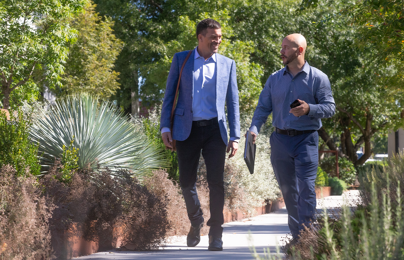 Two men talking and walking on a path outside