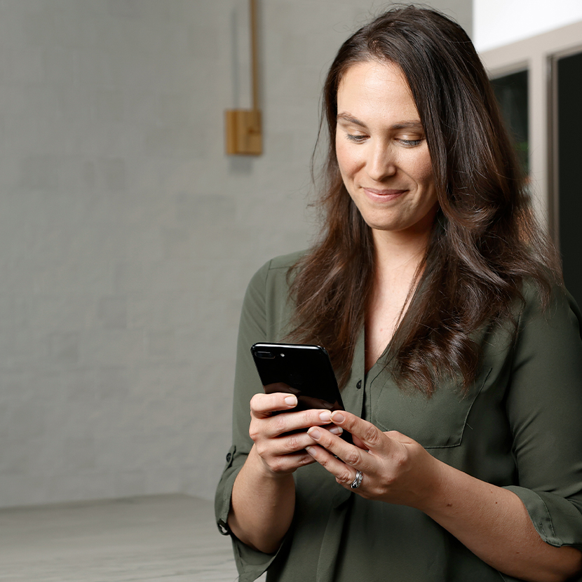 Woman smiling, looking at a cellphone in her hands