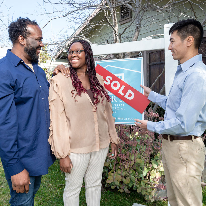 A couple stands by the sold sign of their new house, thanks to TruStage private mortgage insurance