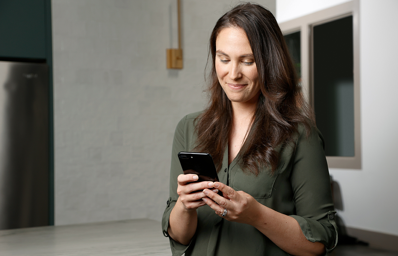 Woman smiling, looking at a cellphone in her hands