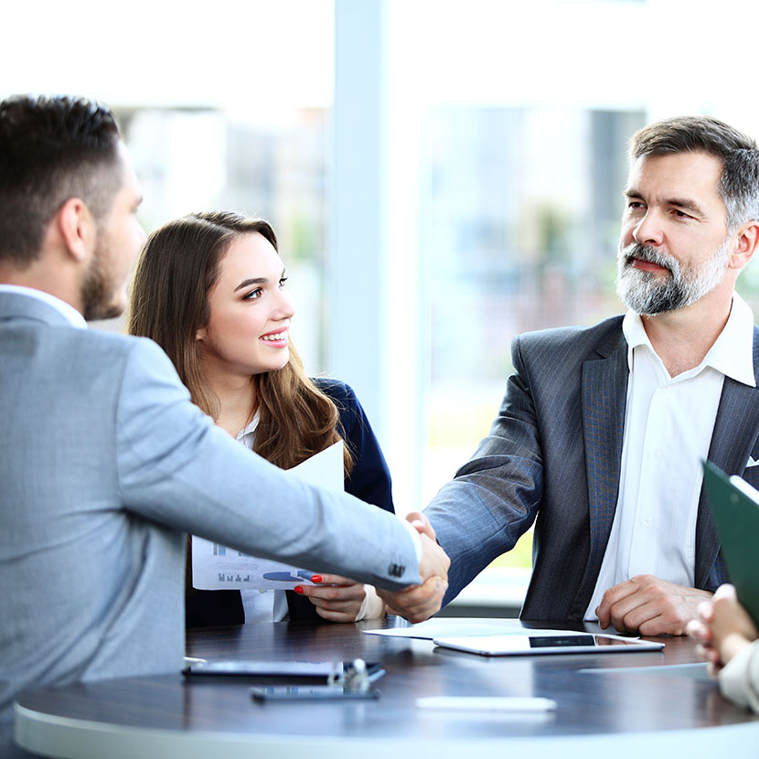 Two men shaking hands with a woman standing next to them talking about TruStage Payment Guard Insurance