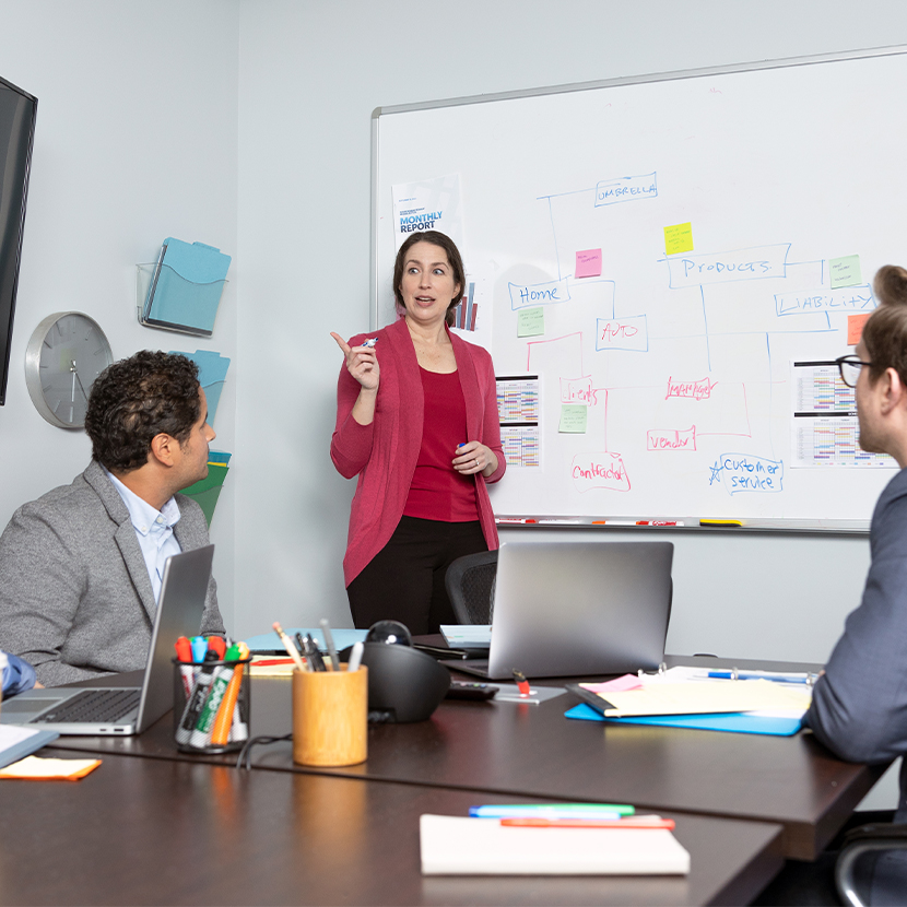 A woman and two men in an office setting talking about Pension Risk Transfer