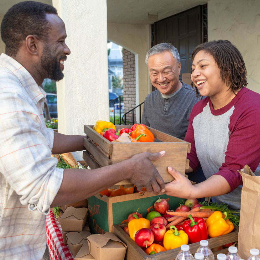A group of people smile about TruStage while looking through produce