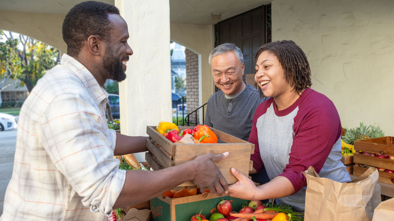 A group of people smile about TruStage while looking through produce
