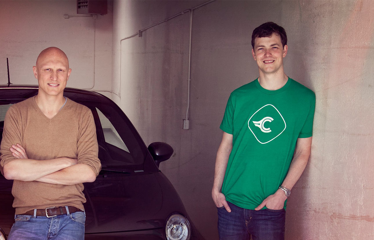 One man leaning against a car, and one man standing