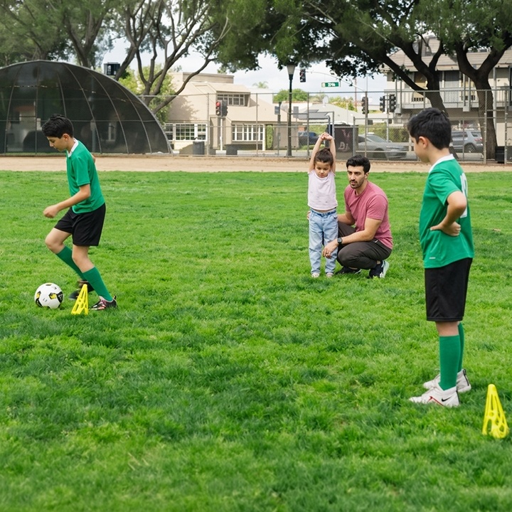 A father watches his children play soccer.