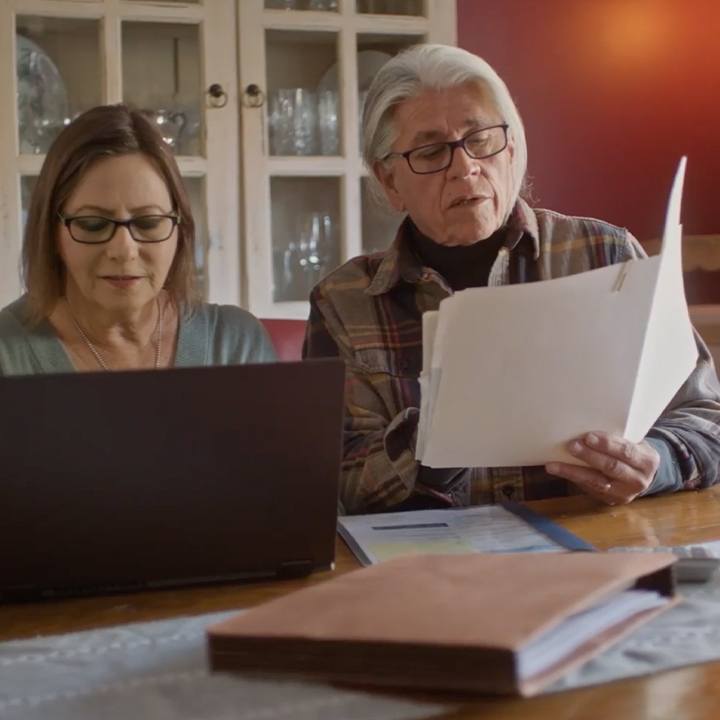 A married couple sits at a desk and tries to locate a lost life insurance policy.