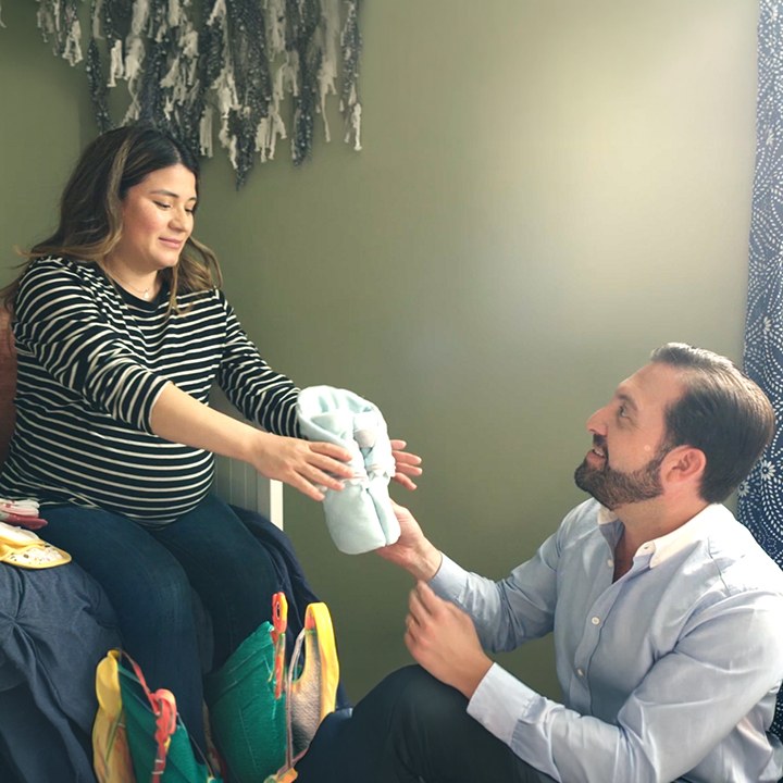 A husband and wife sit in a bedroom and discuss applying for life insurance.