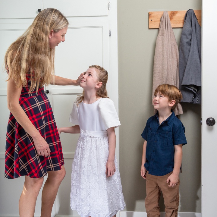 A mother greets her son and daughter at their home.