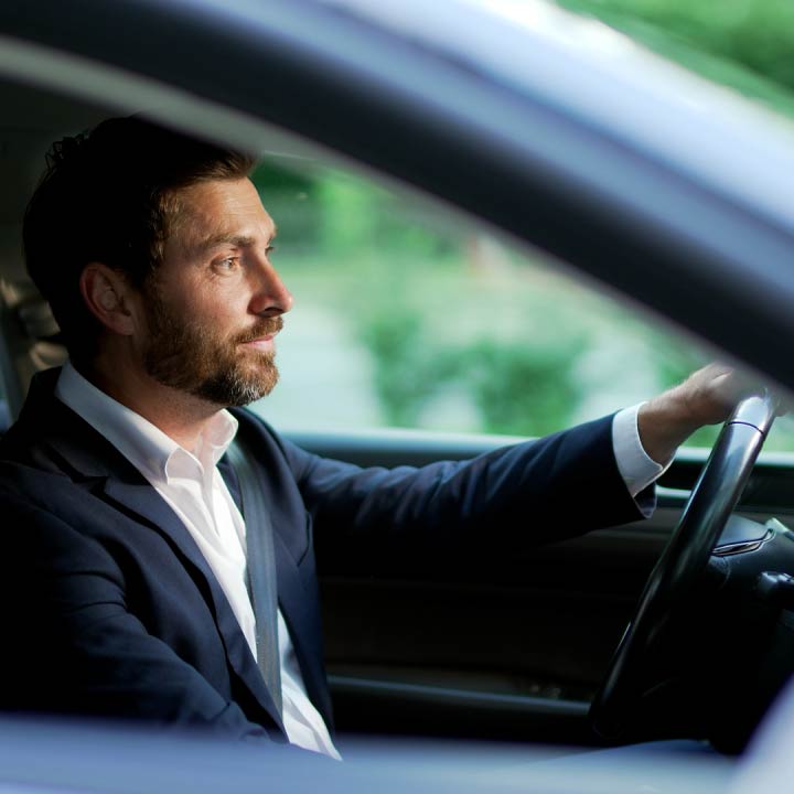 A business professional sits in his car as he drives to work.