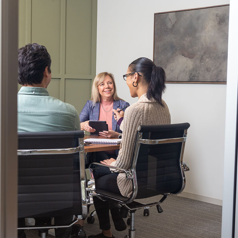 A group of people in a conference room talking about open enrollment